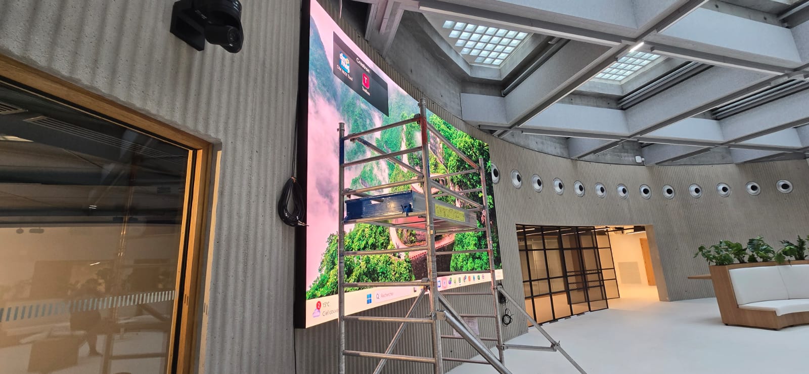 Museum Paris — wide view of curved LED wall integrated into board-marked concrete atrium with coffered ceiling and circular acoustic features