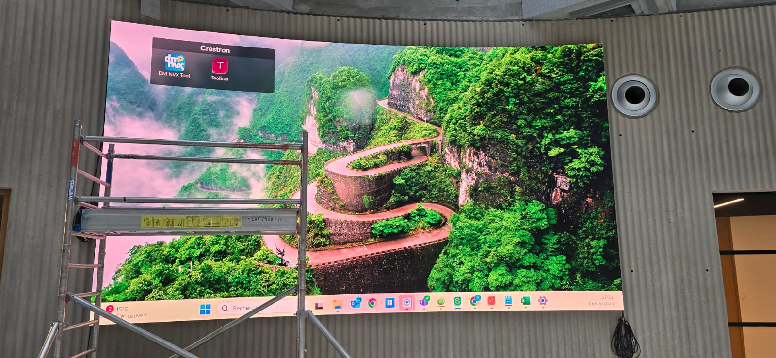 Museum Paris — curved LED video wall live during commissioning, integrated into board-marked concrete atrium wall with mobile access tower in foreground