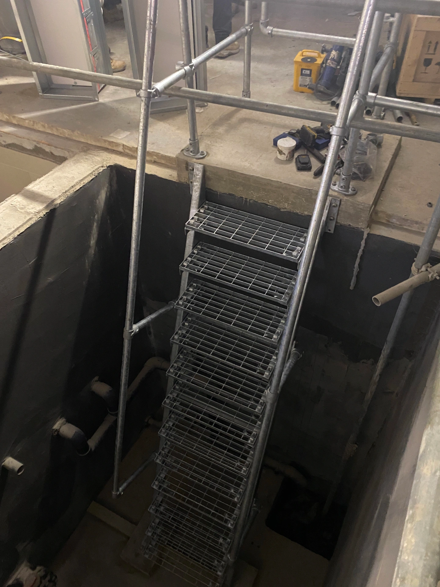Spa — engineered access stair into below-pool plant void with galvanised tread system and edge-protection handrails