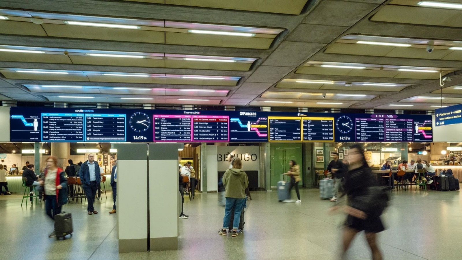 St Pancras International — live passenger information display wall in concourse with passengers in motion