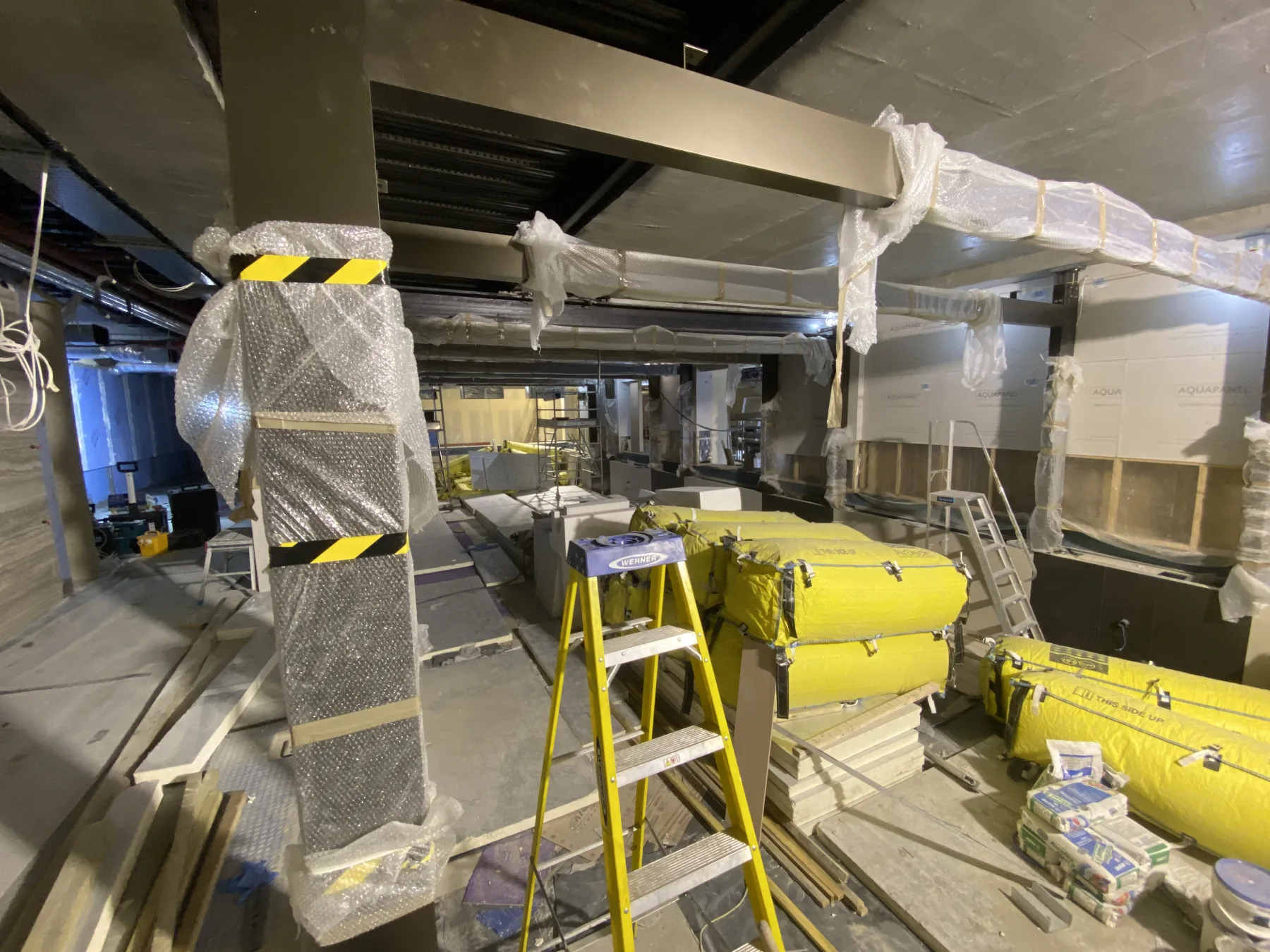 Third Space — protective wrap on aluminium columns and primary beams during adjacent stone and panel fit-out works